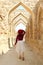 Female Visitor Walking along the Iconic Archways of Ancient Bahrain Fort in Manama, Bahrain