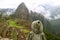 Female visitor wearing raincoat full of raindrops Looking at the Machu Picchu Inca citadel in light rain, Cusco, Peru