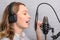Female vocal recording. Young girl with microphone and headphones in recording studio. Recording of vocal, blogger, reading text,