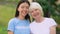 Female volunteer and elderly woman smiling at camera outdoors, nursing home