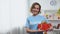 Female volunteer holding gift box in hands smiling on camera, donation, charity