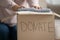 Female volunteer put clothes into cardboard donation box