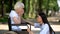 Female volunteer supporting sad elderly woman in wheelchair in hospital park