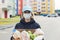 Female volunteer wearing a protective mask walks down the street with a box of groceries, donations