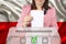 Female voter drops a ballot in a transparent ballot box against the background of the national flag of Poland, concept of state