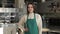 Female waiter in green apron posing at local cafe