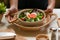 Female waitress hands serving salad with boiled eggs, lettuce and tomato