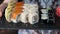 Female waitress show tray of sushi set on black wall background in restaurant.