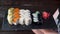 Female waitress show tray of sushi set on a black wooden wall background