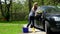 Female washing her car at house yard in garden.