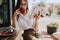 Female wearing glasses at cafe with a digital tablet drinking coffee. Businesswoman drinking coffee at cafe