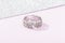 Female wedding silver ring  in floral design with diamonds on pink background with sparkles