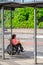Female wheelchair user looks at smartphone while waiting at bus stop