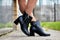 Female winter, autumn or spring black leather shoes on leg of woman outdoors. Fashionable modern photography and