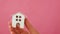 Female woman hand holding miniature toy house isolated on pink background