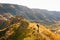 Female woman walks up the hill towards Tmogvi fortress surrounded by golden autumn nature and dramatic landscape in caucasus