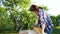 Female woodworker sanding wooden plank with metal brush and blowing off dust