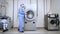 Female worker loading washing machine at hotel laundry. Commercial laundry room