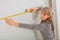 Female worker measuring white wall