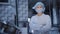 Female worker in medical mask stands near machine tool