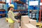 Female worker scanning package with barcode scanner while using digital tablet in warehouse