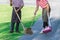 Female worker sweeping yard with broom tool and dustpan in ornamental backyard garden. Woman wear apron with hat sweeping away