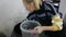 Female worker taking pickled green olives from brine and filling plastic bucket. Artisanal pickles producing