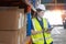 Female worker wearing safety uniform and hard hat using tablet checking inspect goods on shelves in warehouse. women worker check