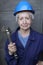 Female worker wearing uniform, blue hardhat and holding large adjustable wrench