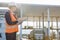 Female worker writing on clipboard while looking at trucks entering in shipping yard