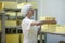 Female worker on yellow cheese production line in an industrial