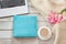 Female workplace with a laptop, cup of coffee, blue notebook, cozy sweater and pink flowers on light background.Top view compositi