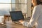 Female writer typing using laptop keyboard at her workplace in the morning. Woman writing blogs online, side view close