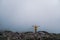 Female in yellow raincoat, jeans shorts standing at top of mountain with view of peaks at horizon. Landscape. Nature.