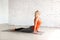 Female yoga indoor. Adult caucasian woman practice upward dog pose on a mat in loft white studio, selective focus.