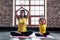 Female yoga instructor training little girl doing stretching exercise sitting in lotus position indoors