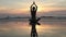 Female in yoga meditation pose at amazing sunset on the sea.