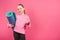 female youngster holding fitness mat and showing thumb up, isolated