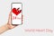 A females hand holds a smartphone with a red heart depicted on it. White background. Copy space. Concept of world heart day,