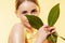 Feminine. Close up of beautiful female face with green leaves over white background. Cosmetics and makeup, natural and