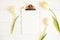 Feminine desktop composition with blank sheet clipboard & white tulips on wooden texture table background, copy space for text. Wo