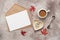 Feminine desktop, home office. Blank card, craft envelope, a cup of coffee with milk and jewelry. Beige grunge background. Modern