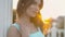 Feminine girl in the blue dress standing on the balcony near the columns at sunset