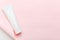 Feminine hygienic product tube on pastel pink background. Shampoo, hand cream, toothpaste white package side view on paper sheet