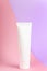 Feminine hygienic product tube on pastel pink and lilac background. Shampoo, hand cream, toothpaste white package side view.