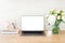 Feminine office desk table with laptop computer with blank white screen, bouquet of flowers, unicorn, stationery and supplies.