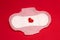 Feminine sanitary pad on a red background. Red heart on the strip. The concept of the female menstrual cycle. The photo