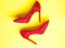 Feminine shoes concept. Footwear with thin high heels, stiletto shoes, top view. Shoes made out of red suede on yellow