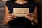 Feminine touch: Hands hold card, box on black wooden table. Graceful presentation.