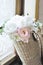 Feminine wedding still life composition. Straw French basket bag with pink peonies flowers and eucalyptus bouquet near